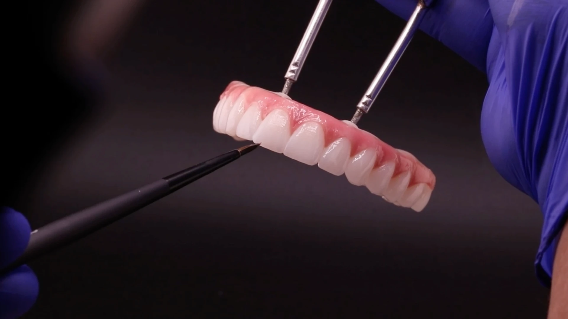 dental technician painting an upper all-on-4 implant bridge